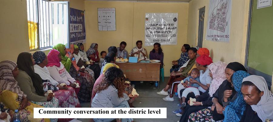Women, parents and local officials sit in a circle at a district level community conversation about inclusive education.